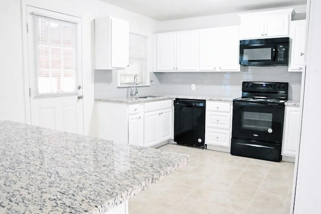 kitchen featuring white cabinets, light stone countertops, black appliances, and a sink