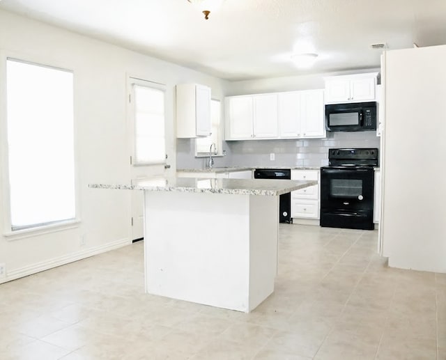 kitchen featuring sink, a kitchen island, white cabinetry, black appliances, and light stone countertops