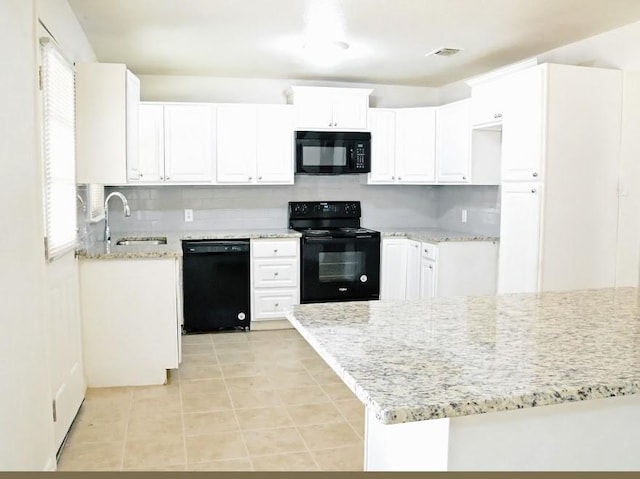 kitchen with visible vents, black appliances, a sink, light stone counters, and backsplash