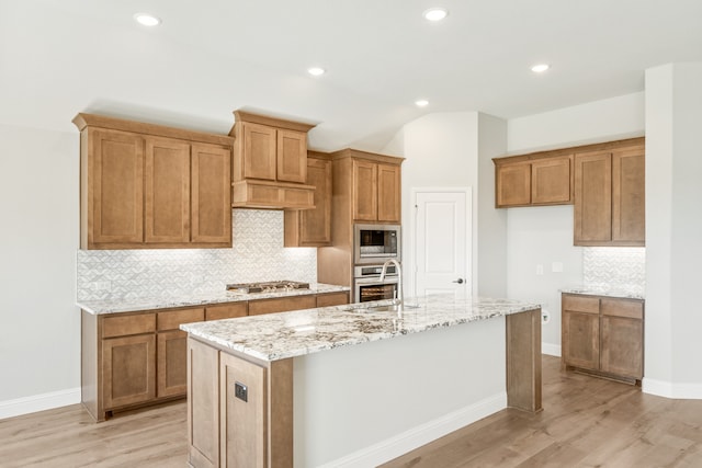 kitchen with sink, an island with sink, appliances with stainless steel finishes, and light hardwood / wood-style flooring