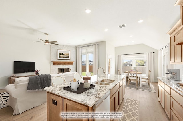 kitchen with a fireplace, sink, light hardwood / wood-style flooring, dishwasher, and an island with sink