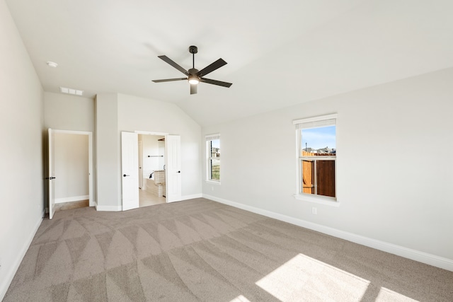 unfurnished bedroom featuring light colored carpet, vaulted ceiling, and ceiling fan