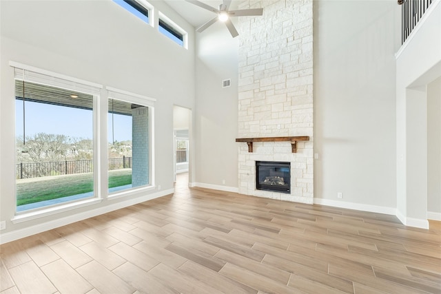 unfurnished living room with a high ceiling, a fireplace, and ceiling fan