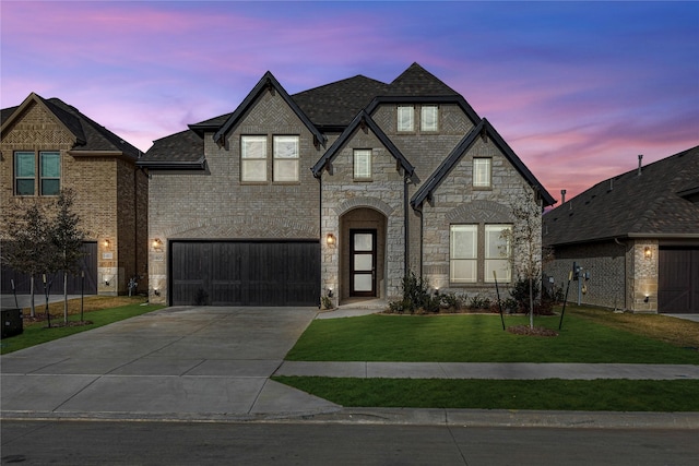 french country style house featuring a lawn and a garage