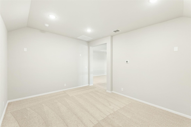 unfurnished room featuring lofted ceiling and light colored carpet