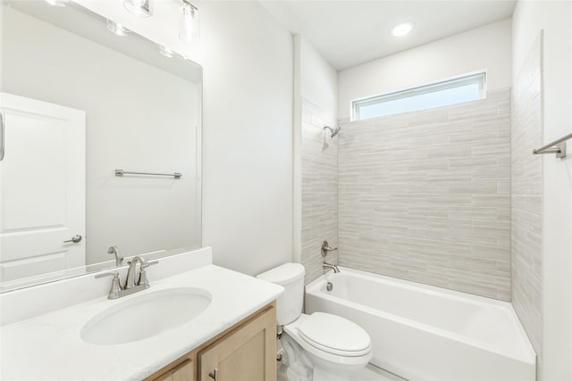 full bathroom featuring tiled shower / bath, vanity, and toilet