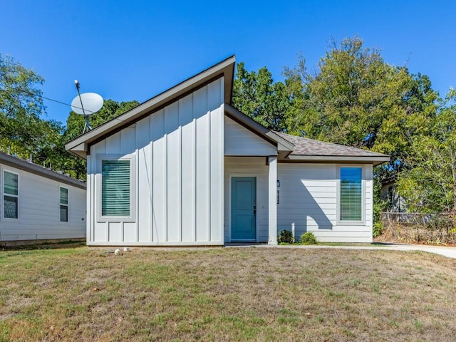 view of front facade with a front lawn, board and batten siding, and a shingled roof