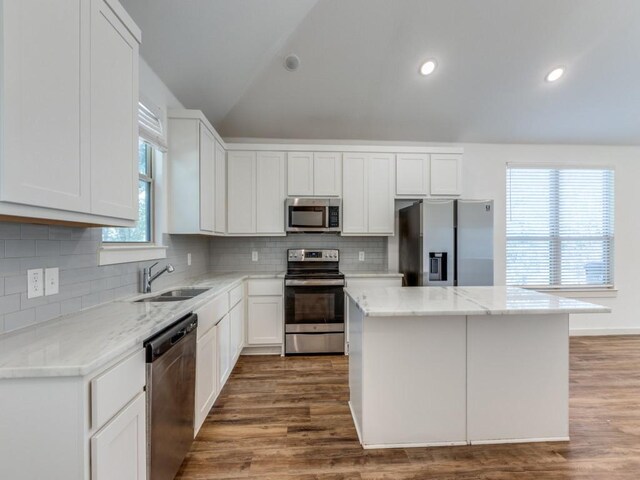 723 E Maple Row, Denison, TX 75021 - kitchen with stainless steel appliances, lofted ceiling, light stone counters, decorative backsplash, and white cabinetry