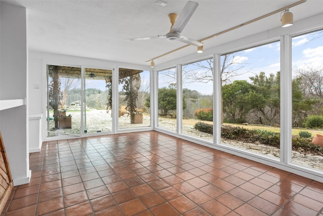 unfurnished sunroom with ceiling fan, track lighting, and a healthy amount of sunlight