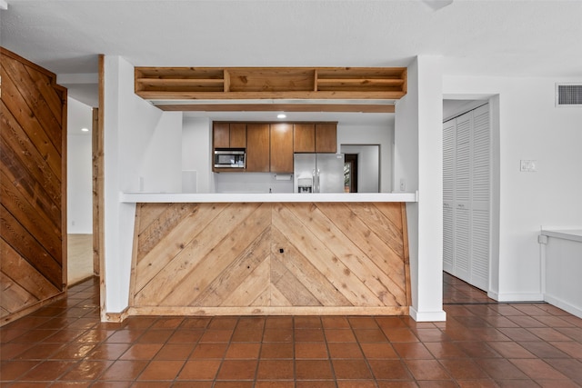 kitchen with dark tile patterned floors, stainless steel appliances, and kitchen peninsula