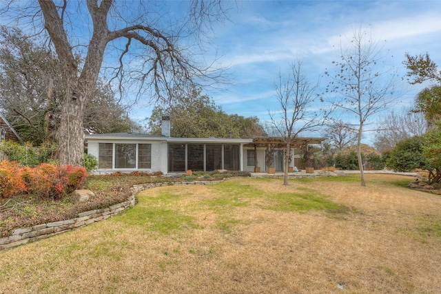 back of property featuring a lawn and a sunroom