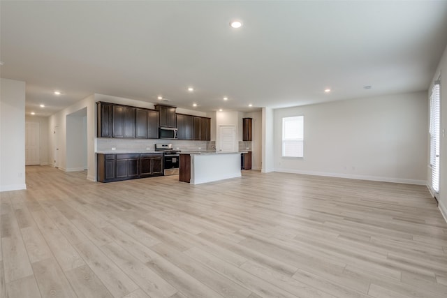 3725 Blooming Prairie Dr, Crandall, TX 75114 - kitchen featuring decorative backsplash, dark brown cabinets, appliances with stainless steel finishes, light wood-style floors, and open floor plan