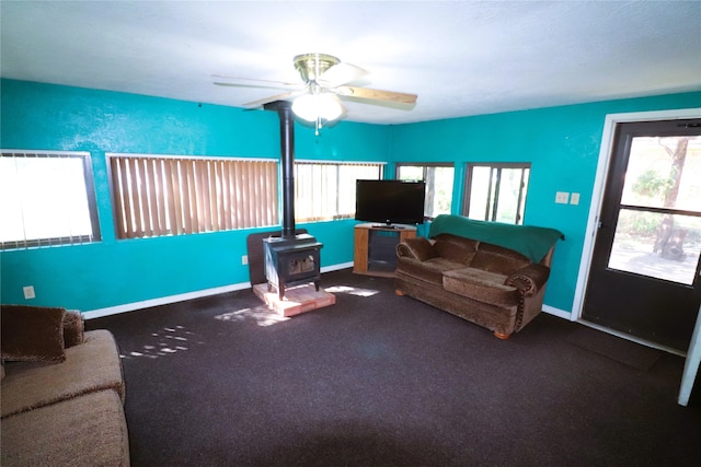 carpeted living room featuring ceiling fan and a wood stove