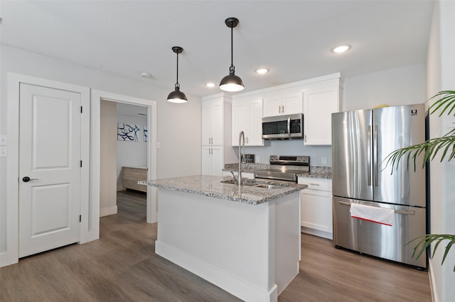 kitchen featuring pendant lighting, hardwood / wood-style flooring, a kitchen island with sink, white cabinetry, and stainless steel appliances