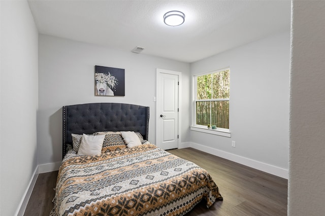 bedroom featuring a textured ceiling and dark hardwood / wood-style flooring