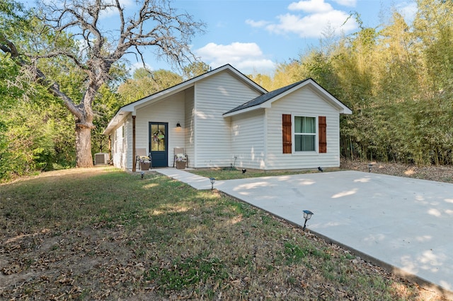 view of front of property featuring central AC unit, a front lawn, and a patio area