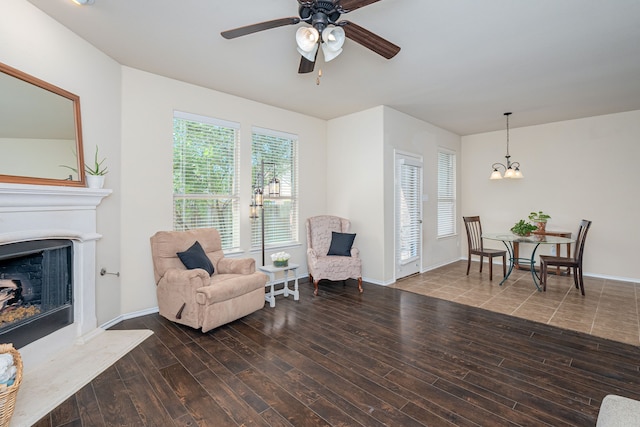 living area with ceiling fan with notable chandelier and dark hardwood / wood-style floors