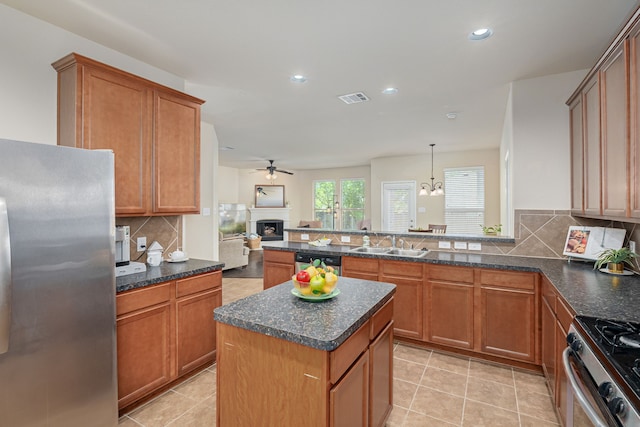 kitchen featuring appliances with stainless steel finishes, hanging light fixtures, tasteful backsplash, ceiling fan with notable chandelier, and a kitchen island