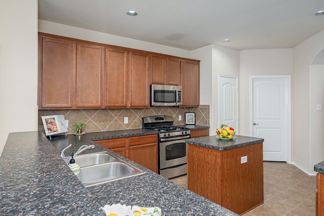 kitchen featuring a center island, tasteful backsplash, sink, appliances with stainless steel finishes, and light tile patterned floors