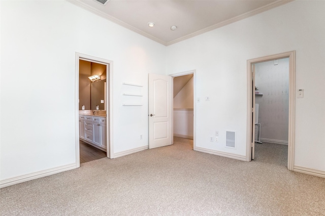 unfurnished bedroom featuring light carpet, visible vents, a spacious closet, a closet, and crown molding