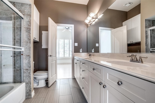 bathroom with visible vents, toilet, a ceiling fan, a shower with shower door, and a sink