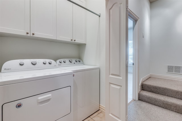 laundry room featuring light carpet, separate washer and dryer, and cabinets