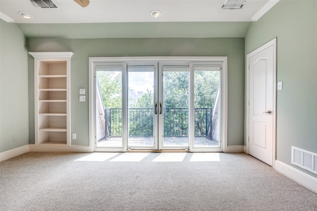 carpeted spare room with ceiling fan, plenty of natural light, and built in features