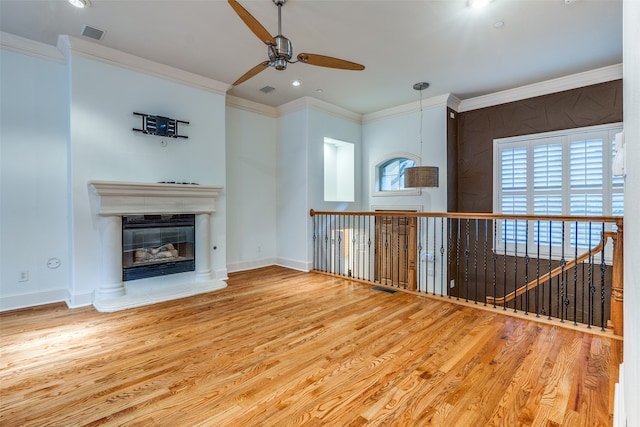 unfurnished living room featuring crown molding, a wealth of natural light, ceiling fan, and hardwood / wood-style flooring