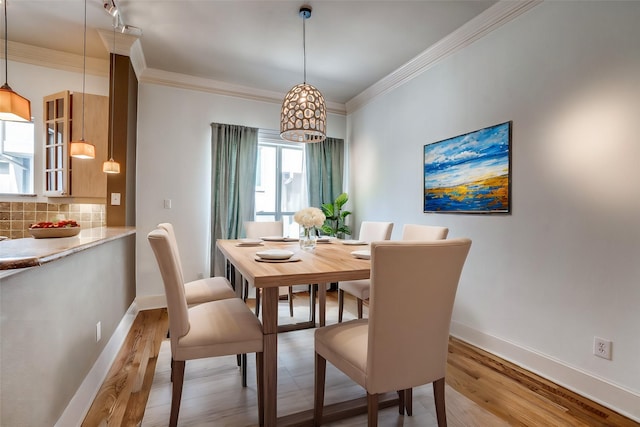 dining area with crown molding, baseboards, and light wood-style floors