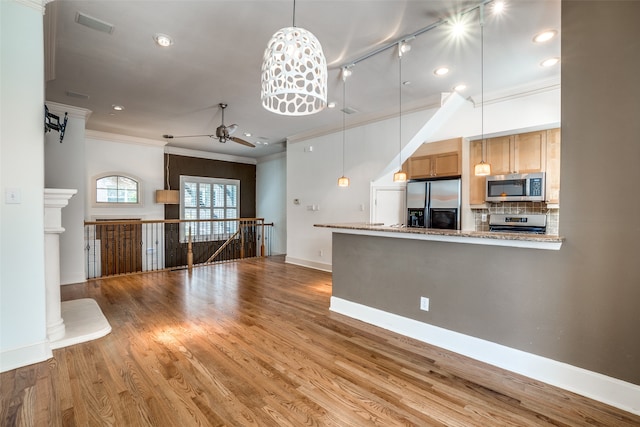 kitchen featuring ceiling fan, ornamental molding, wood-type flooring, stainless steel appliances, and decorative backsplash