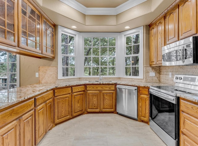 kitchen with a sink, tasteful backsplash, light stone counters, and stainless steel appliances