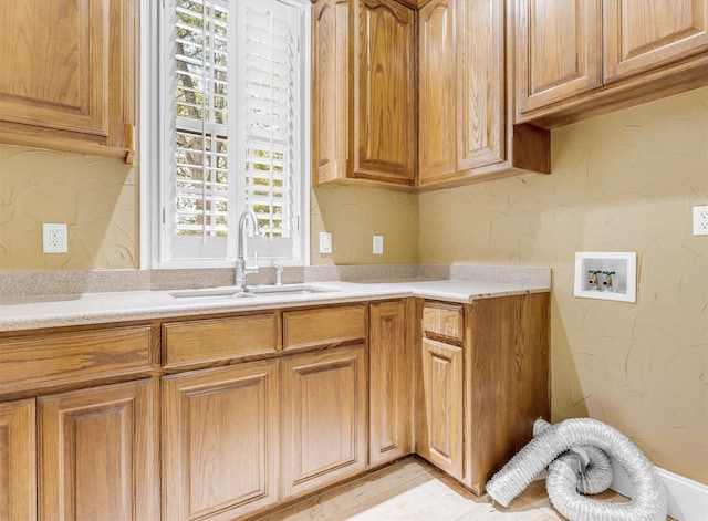 kitchen featuring a sink, light countertops, and a textured wall