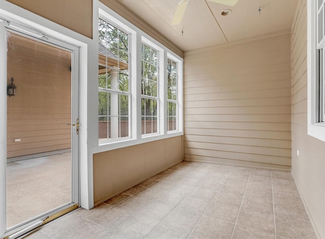 unfurnished sunroom featuring wooden walls and a ceiling fan