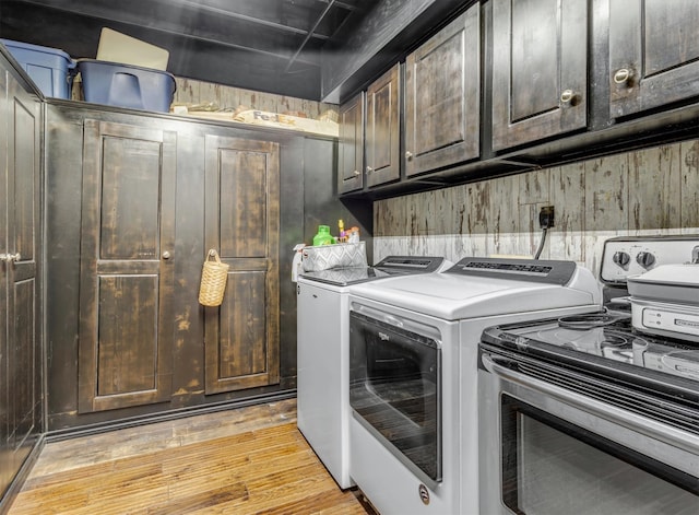 clothes washing area featuring separate washer and dryer, light hardwood / wood-style flooring, and cabinets