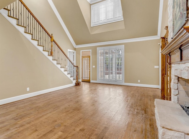 unfurnished living room with stairs, baseboards, ornamental molding, and wood finished floors