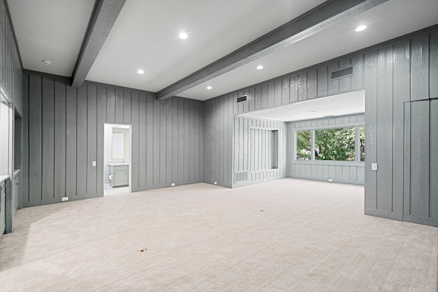 unfurnished room featuring wooden walls, beam ceiling, and light colored carpet