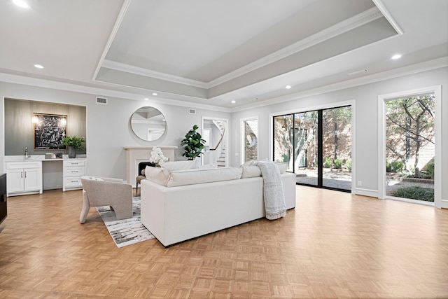 living room featuring ornamental molding, a tray ceiling, and light parquet floors