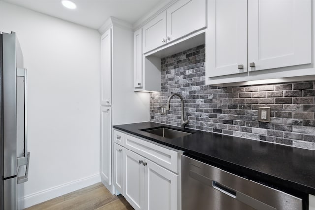 kitchen with white cabinets, appliances with stainless steel finishes, sink, and light hardwood / wood-style flooring