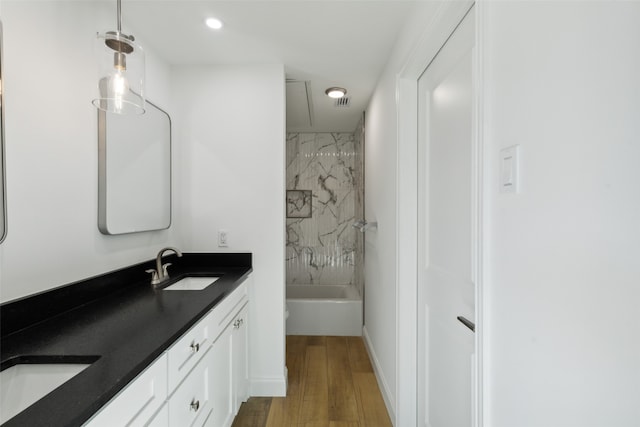 bathroom with wood-type flooring, tiled shower / bath combo, and vanity