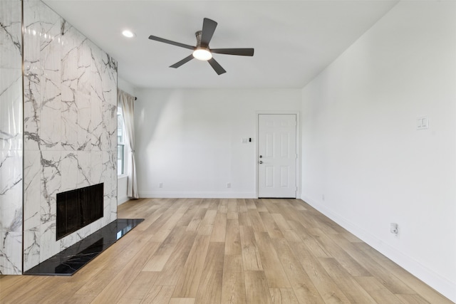 unfurnished living room with ceiling fan, light hardwood / wood-style flooring, and a high end fireplace