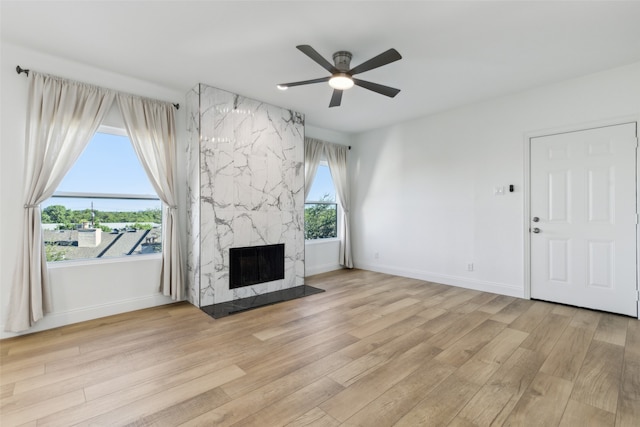 unfurnished living room with ceiling fan, light hardwood / wood-style flooring, and a premium fireplace