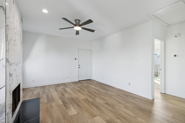 unfurnished living room featuring a high end fireplace, light hardwood / wood-style floors, and ceiling fan