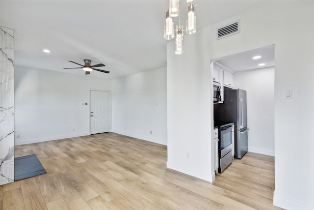 interior space featuring appliances with stainless steel finishes, ceiling fan with notable chandelier, white cabinetry, and light hardwood / wood-style flooring