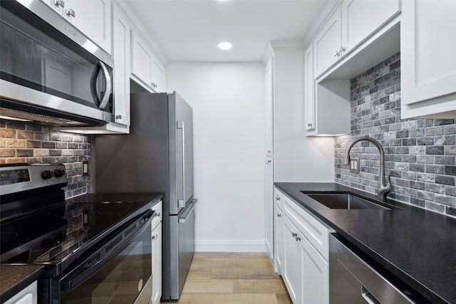 kitchen featuring appliances with stainless steel finishes, white cabinetry, tasteful backsplash, light hardwood / wood-style flooring, and sink