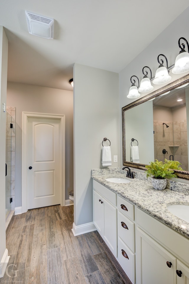 bathroom with a shower with door, hardwood / wood-style flooring, vanity, and toilet