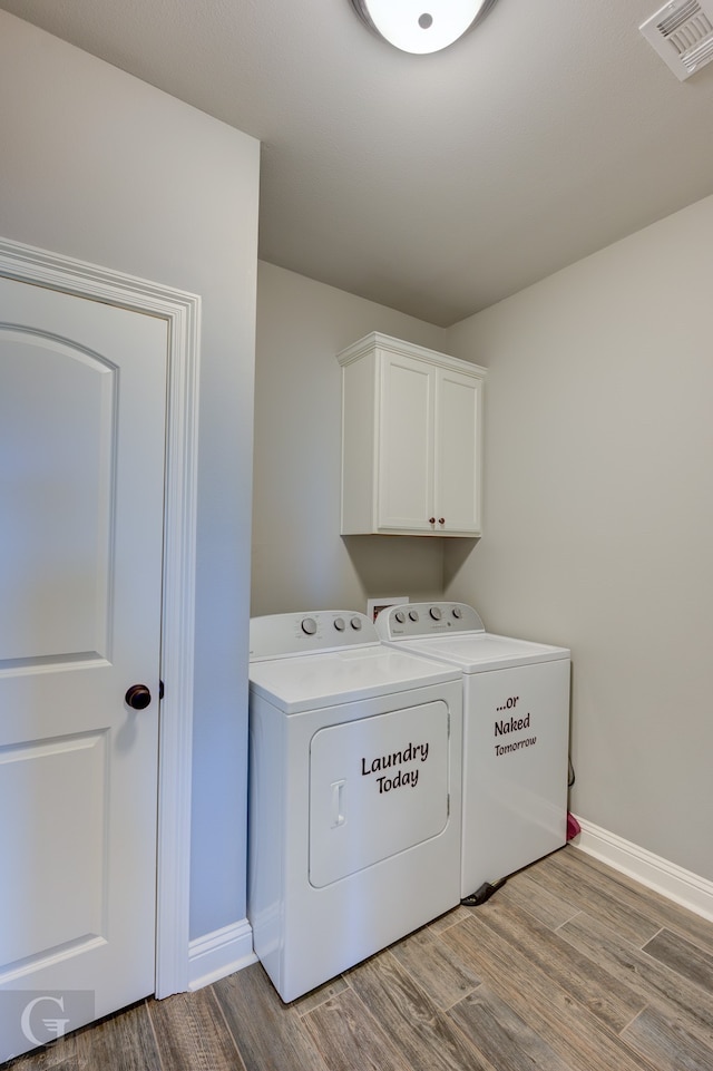 laundry area with cabinets, washer and dryer, and light hardwood / wood-style flooring