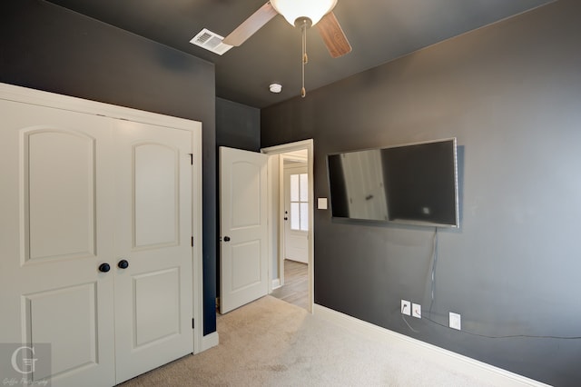 bedroom with light carpet, ceiling fan, and a closet