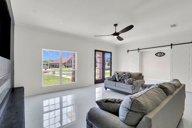 tiled living room with ornamental molding, ceiling fan, and a barn door