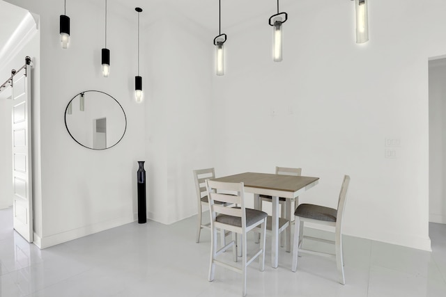 dining space with a barn door and light tile patterned flooring