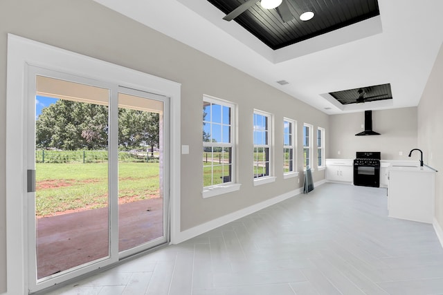 unfurnished living room with ceiling fan, light tile patterned floors, sink, and a healthy amount of sunlight